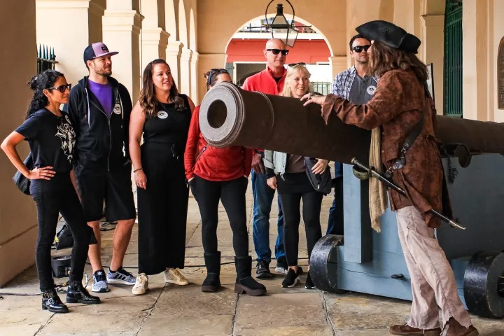 Tour group standing at cannon outside The Cabildo during French Quarter Pirate Tour.